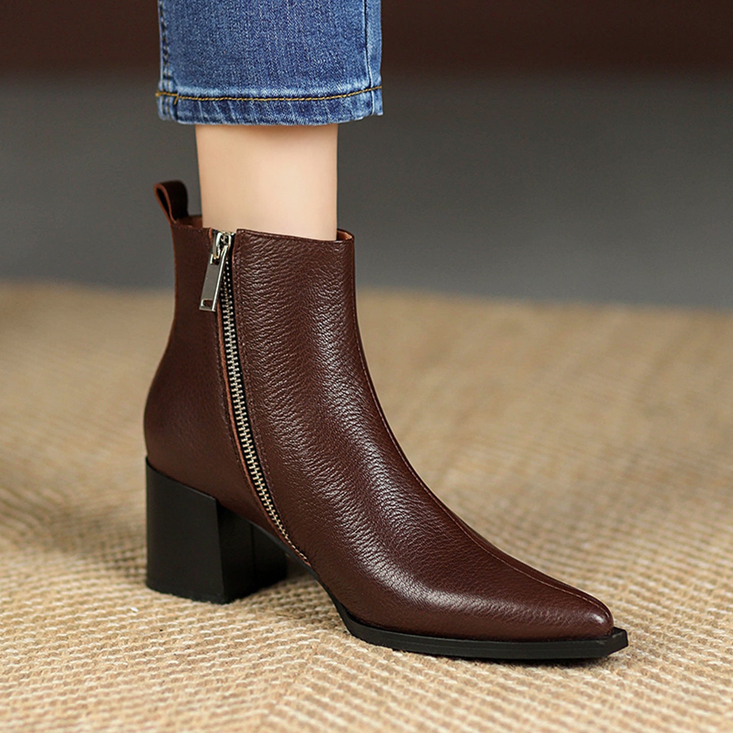 Brown ankle boot with a zipper on a textured surface