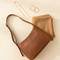 Brown leather shoulder bag, gold hoop earrings, gold chain necklace and a camel wool scarf