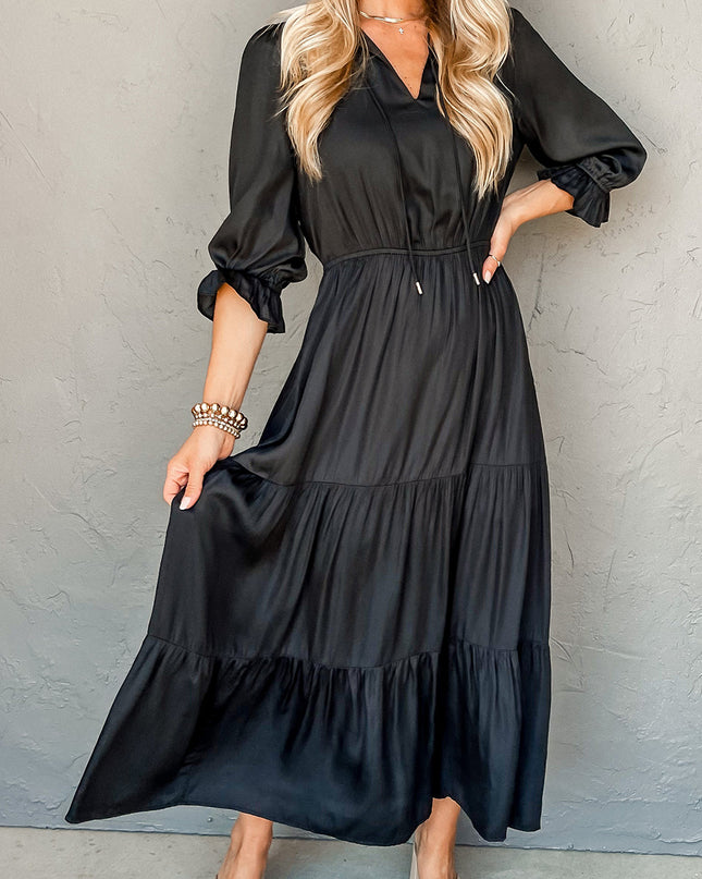 Woman wearing a black dress with long sleeves against a gray background