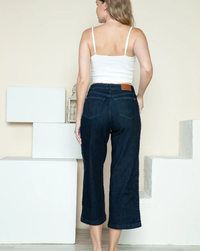 Woman wearing a white top and dark blue jeans standing in a minimalistic room.