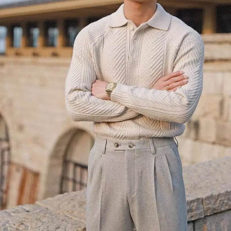 Person wearing a beige knitted sweater and light gray pants standing outdoors.