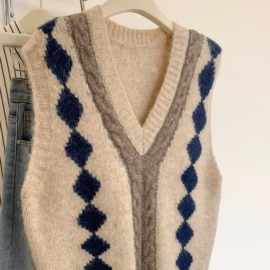 Beige sweater vest with blue and brown pattern on a hanger