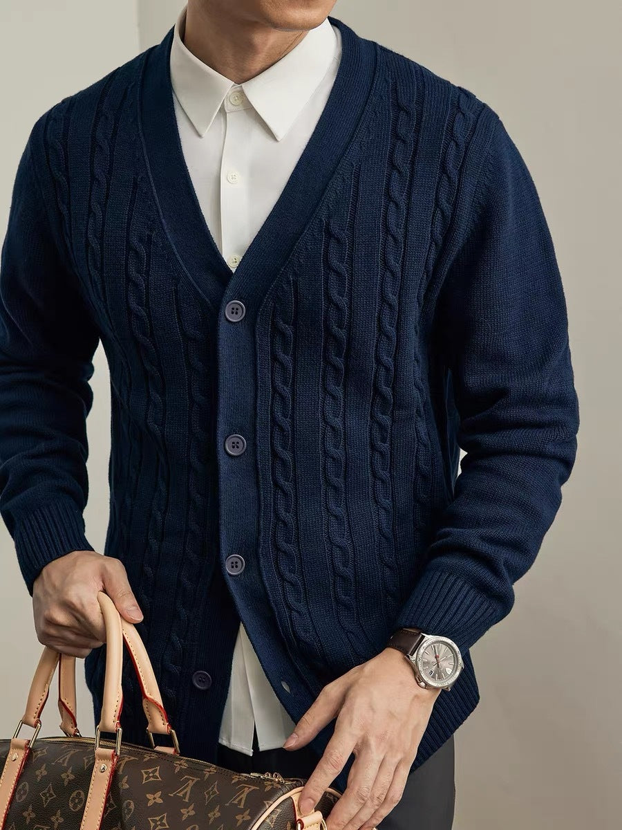 Person wearing a navy blue cable knit cardigan holding a Louis Vuitton handbag.