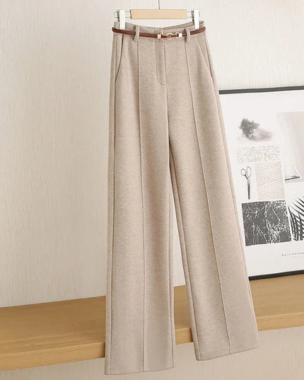 Beige pants on a hanger against a neutral wall with a framed picture in the background.