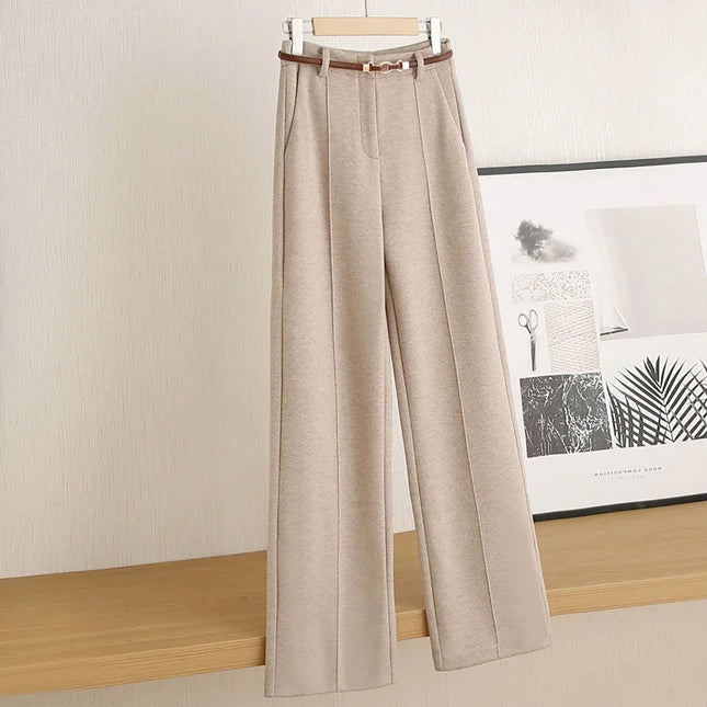 Beige pants on a hanger against a neutral wall with a framed picture in the background.