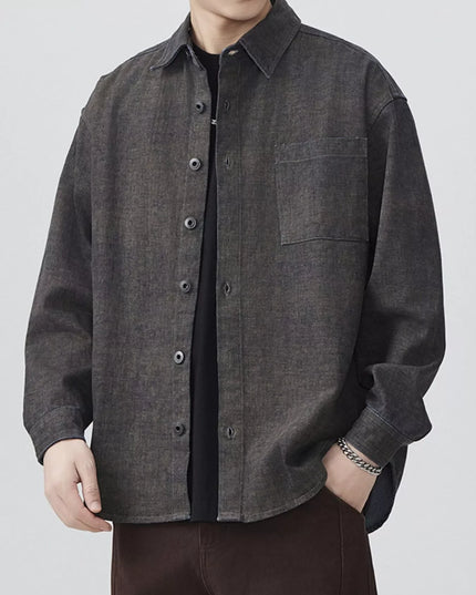 Person wearing a dark gray button-up shirt on a white background