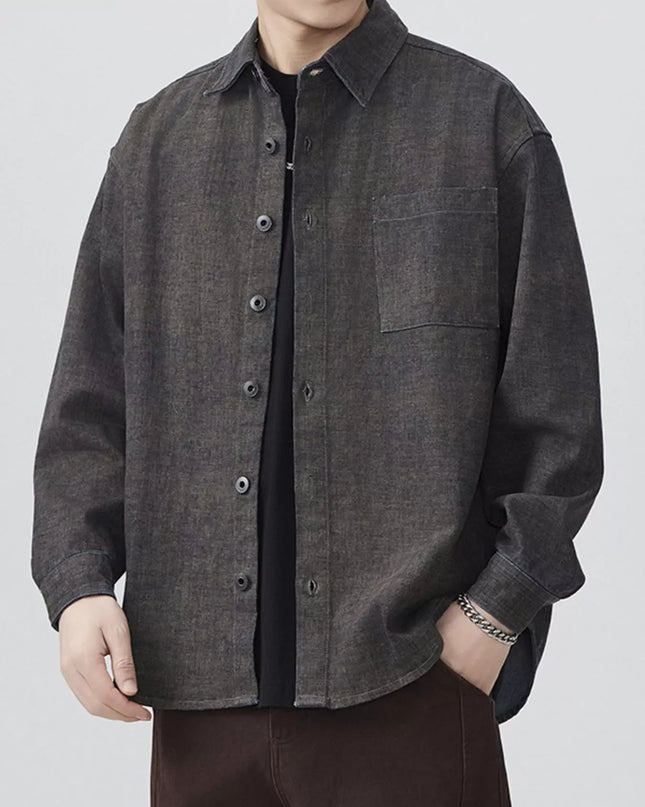 Person wearing a dark gray button-up shirt on a white background