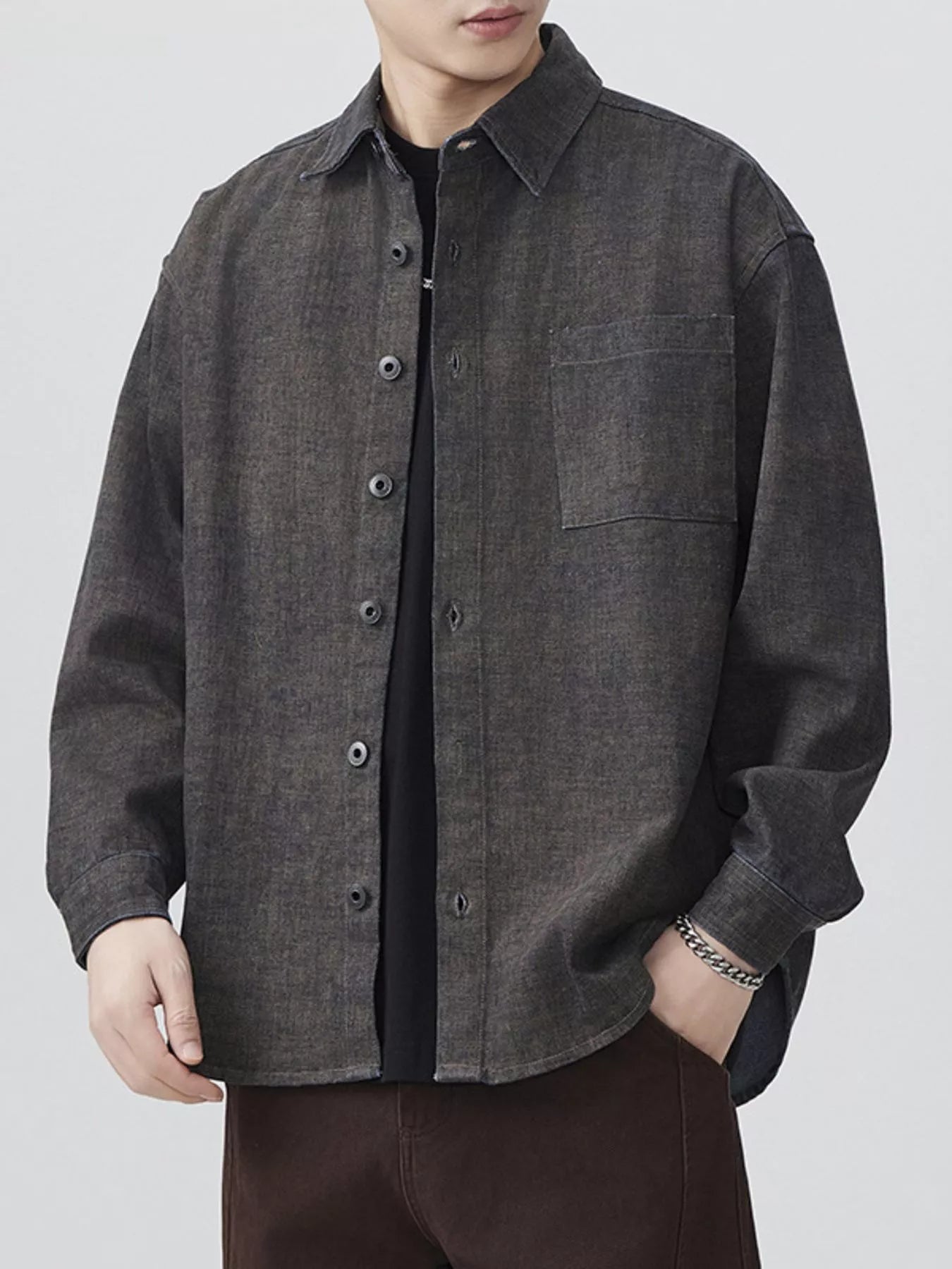 Person wearing a dark gray button-up shirt on a white background