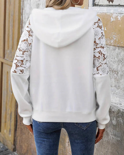 White hoodie with lace sleeves worn by a person against a textured wall.