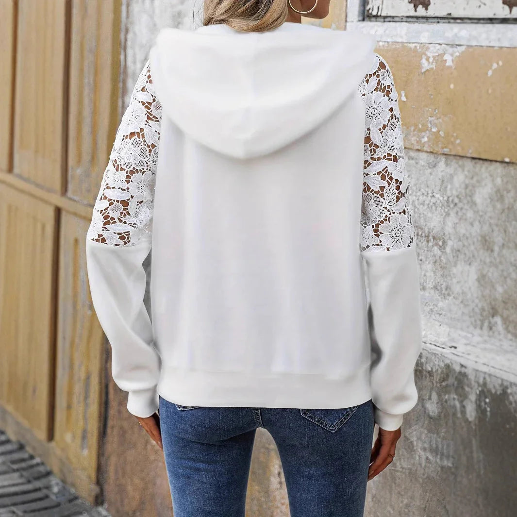 White hoodie with lace sleeves worn by a person against a textured wall.