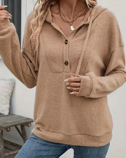 Person wearing a brown ribbed sweater with buttons indoors.