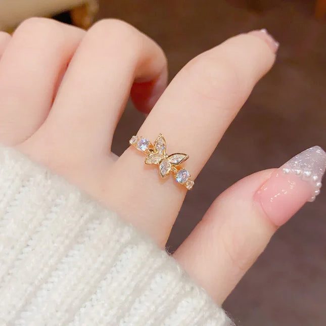 Gold butterfly ring on a finger with a blurred background