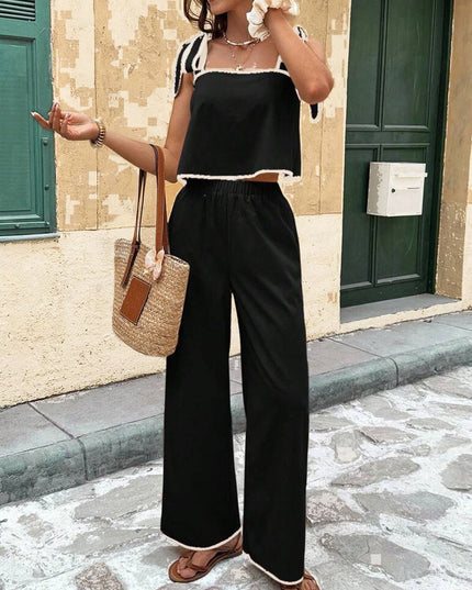 Woman in black outfit with wide-leg pants standing on a street.