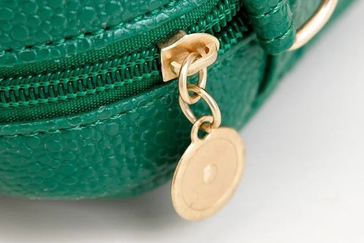 Green textured purse with a gold zipper pull and tag on a light gray background