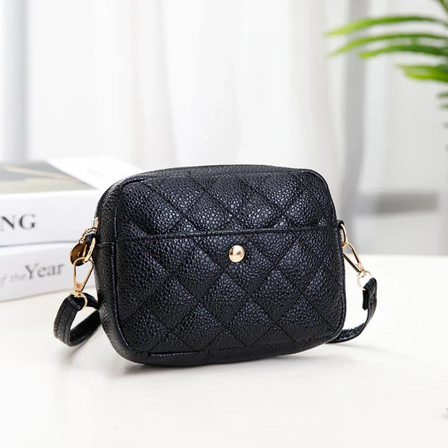 Black quilted handbag on a white surface with a blurred background