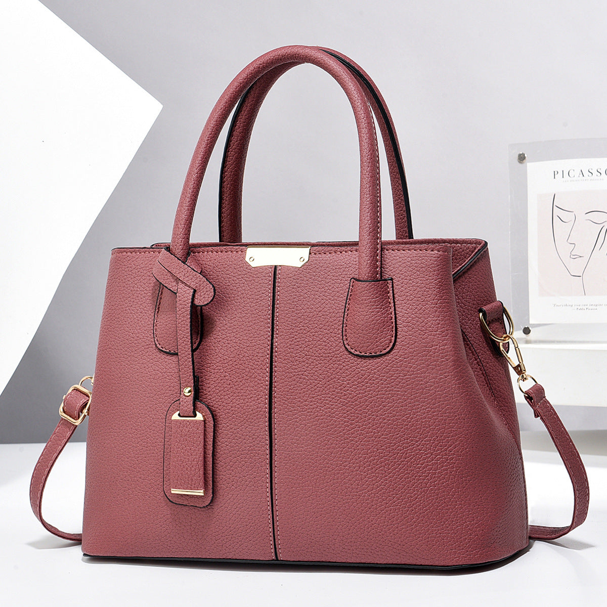 Pink handbag with gold accents on a white background