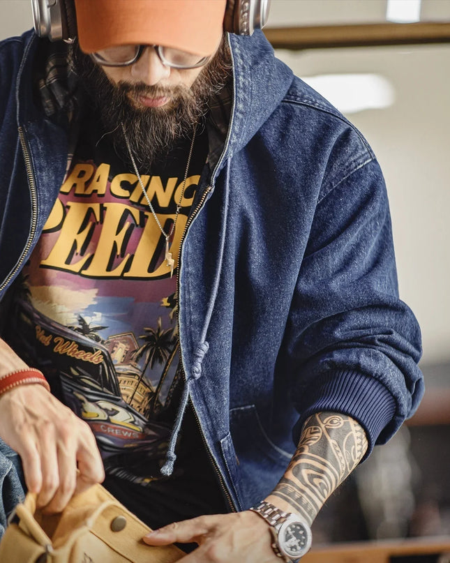 Man wearing a denim jacket and 'Racing Speed' t-shirt, holding a leather bag.