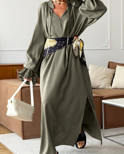 Person wearing a long olive green dress with a belt in a living room setting