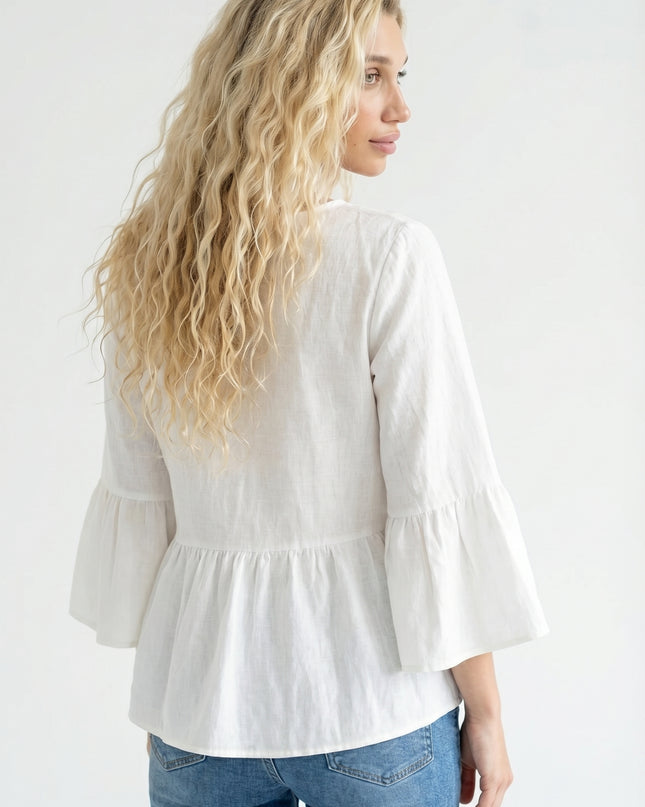Woman wearing a white blouse with ruffled sleeves and blue jeans on a white background