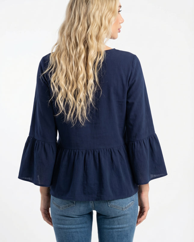 Woman wearing a navy blue blouse with ruffled sleeves and hem on a white background