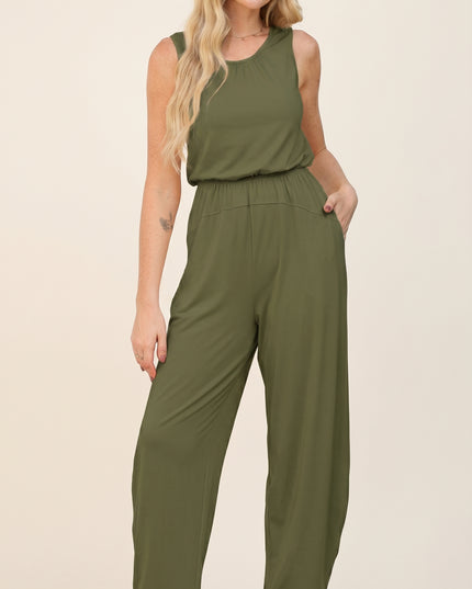 Woman wearing an olive green jumpsuit on a beige background