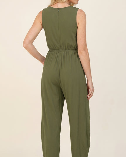 Woman wearing an olive green jumpsuit on a beige background