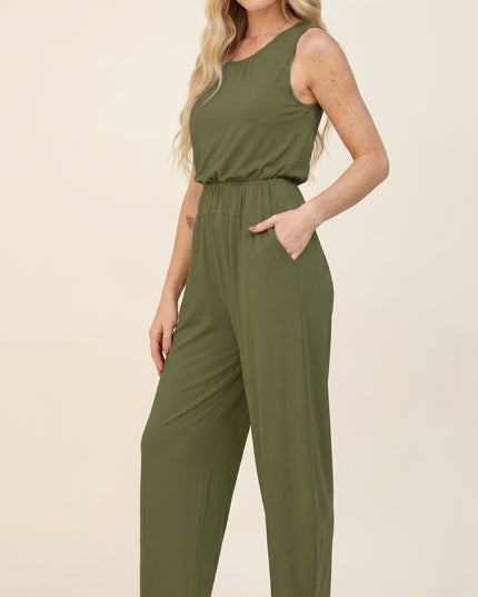 Woman wearing an olive green jumpsuit on a beige background