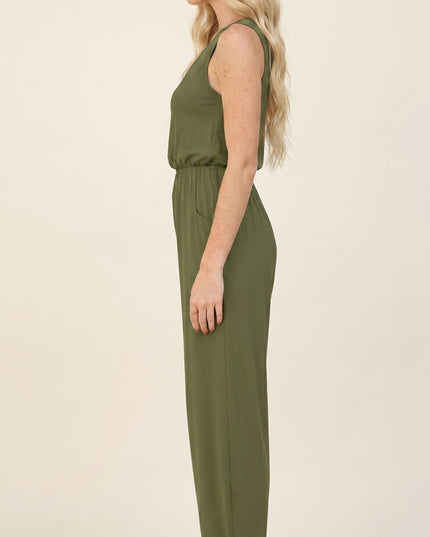 Woman wearing an olive green jumpsuit on a beige background