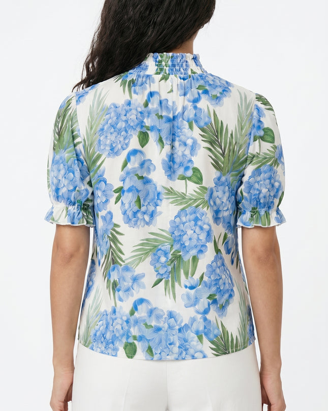 Woman wearing a floral blouse with blue flowers and green leaves on a white background