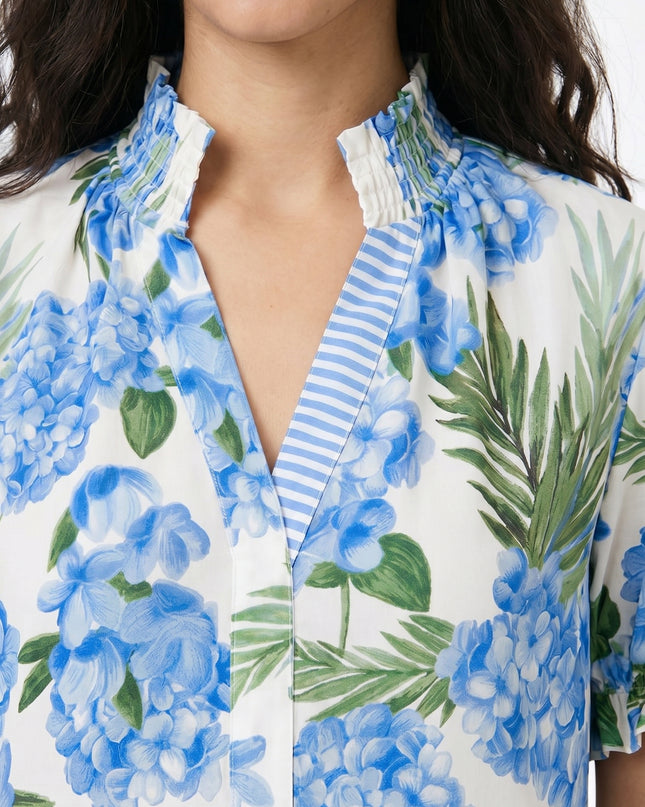Woman wearing a floral blouse with blue flowers and green leaves on a white background
