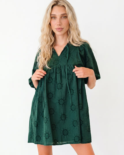 Woman wearing a green dress with floral patterns on a white background