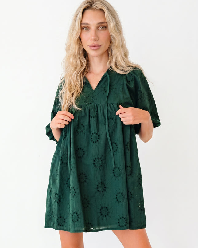 Woman wearing a green dress with floral patterns on a white background