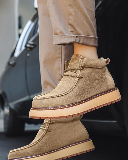 Brown suede boots with beige soles worn by a person, with a car in the background.