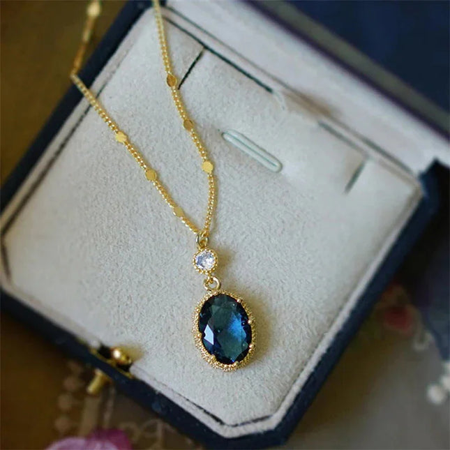 Gold necklace with a blue pendant on a display box