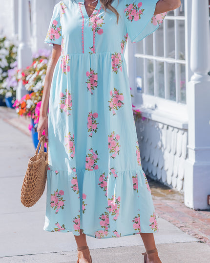 Woman wearing a light blue floral dress standing on a porch.