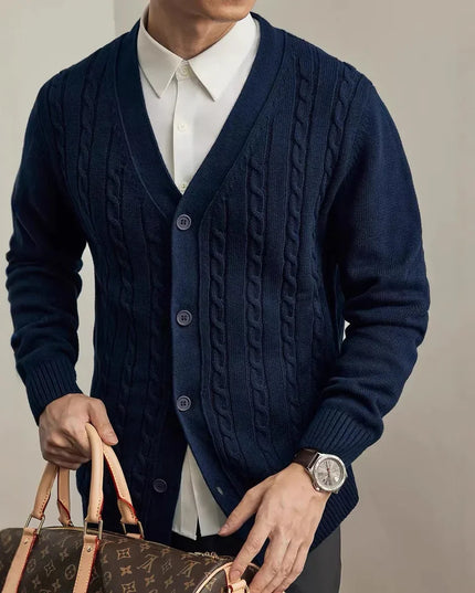 Person wearing a navy blue cable knit cardigan holding a brown leather handbag against a neutral background