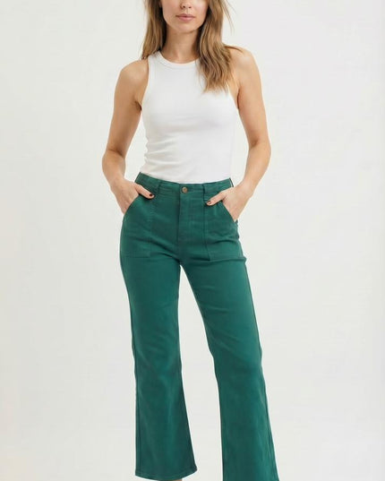 Woman wearing a white tank top and green pants on a white background