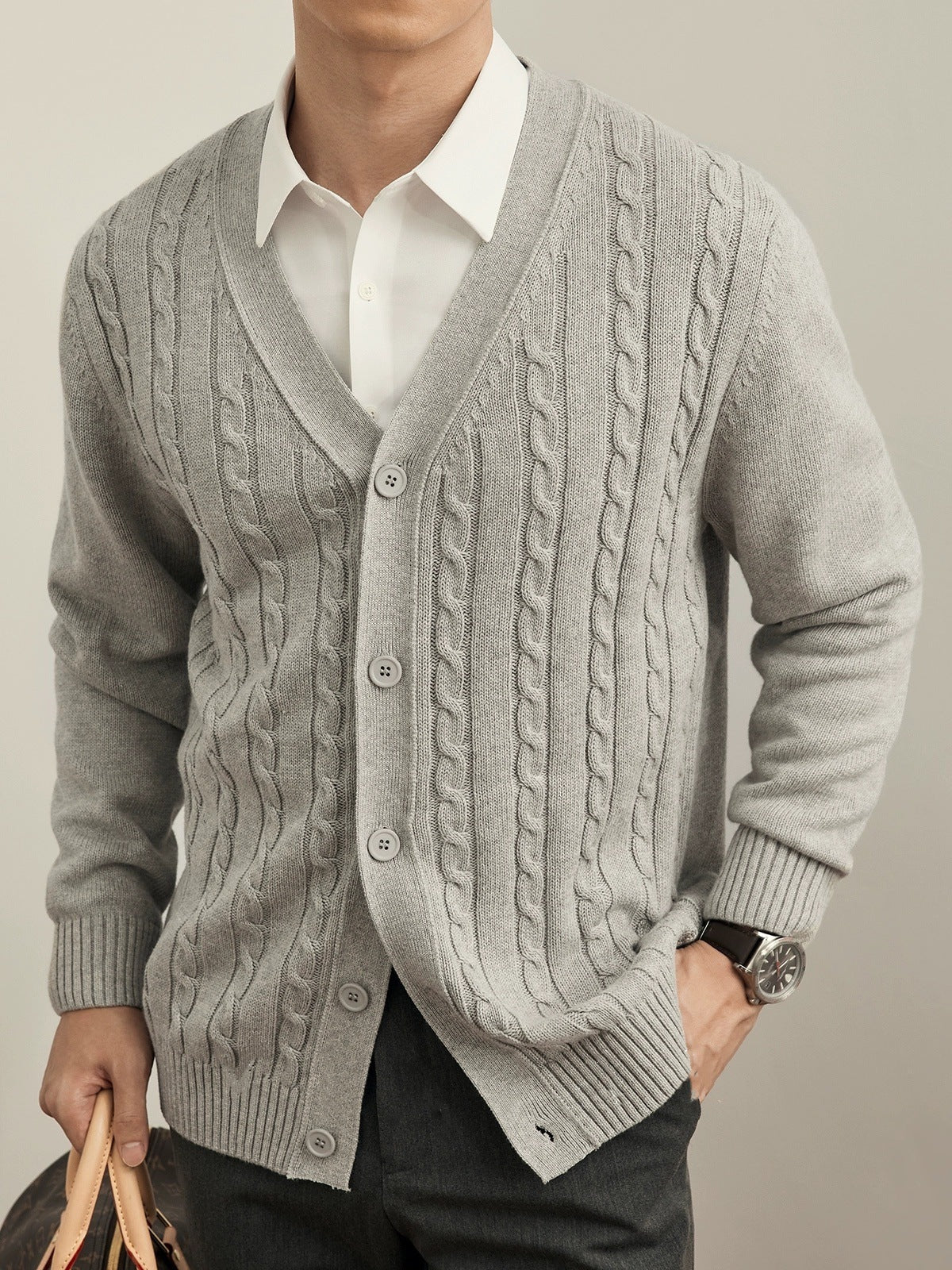 Gray cable knit cardigan worn by a person on a plain background