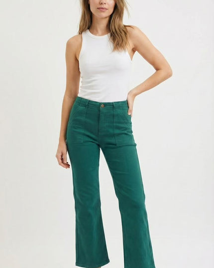 Woman wearing a white tank top and green pants on a white background