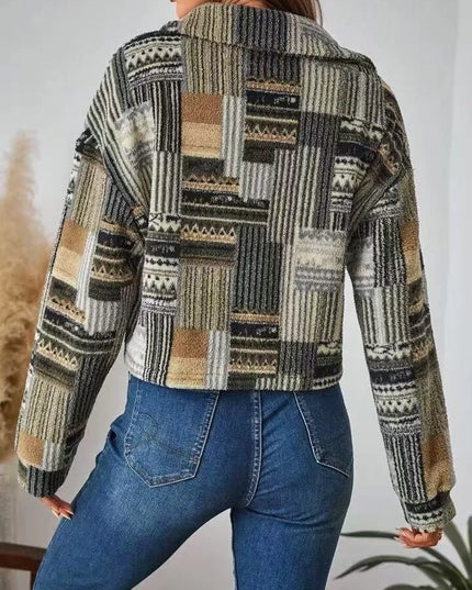 Person wearing a patterned jacket and blue jeans against a neutral background