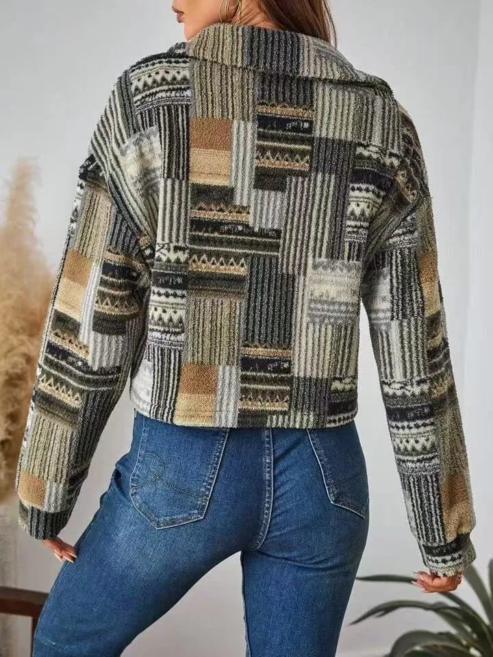 Person wearing a patterned jacket and blue jeans against a neutral background