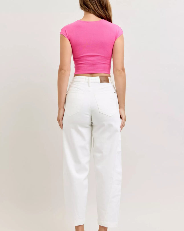 Person wearing a pink top and white pants on a plain background