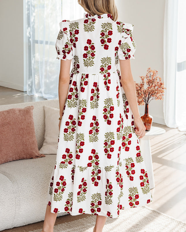 Woman wearing a white dress with red floral pattern in a living room.