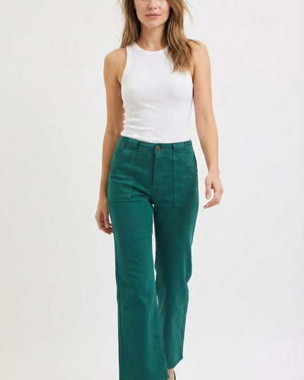 Woman wearing a white sleeveless top and teal pants on a white background