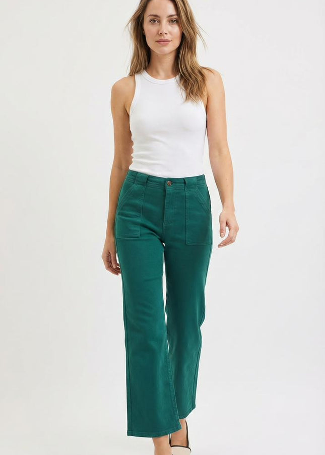 Woman wearing a white sleeveless top and teal pants on a white background