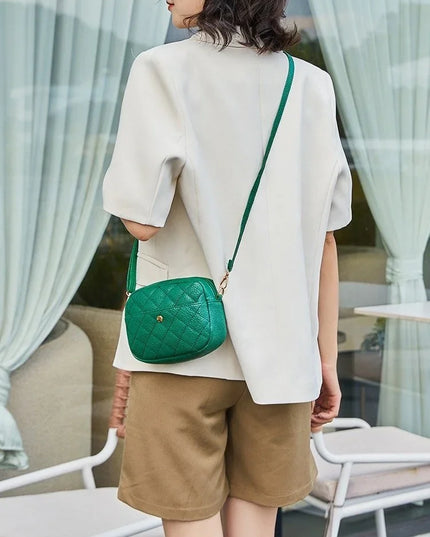 Person wearing a white top and brown shorts with a green handbag outdoors.