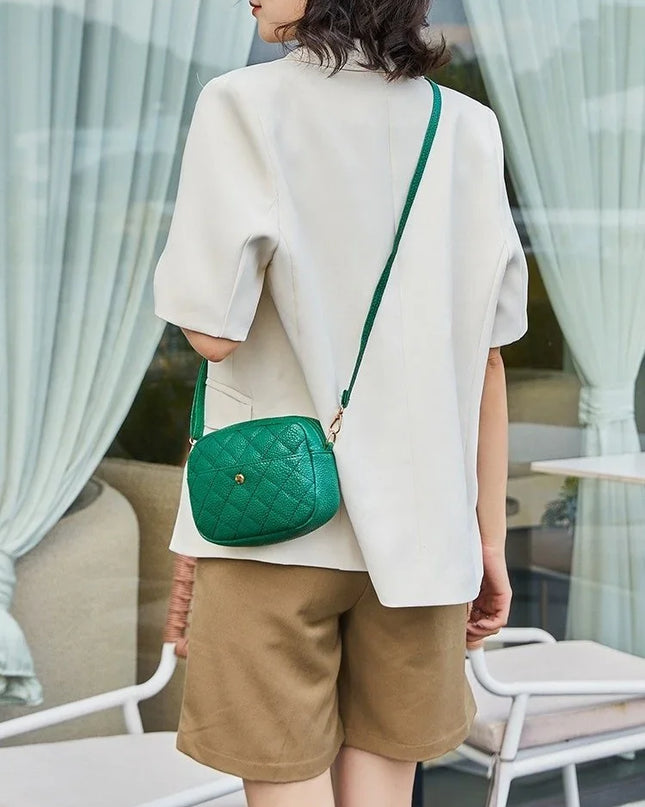 Person wearing a white top and brown shorts with a green handbag outdoors.