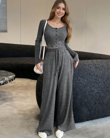 Woman wearing a gray jumpsuit standing in a modern indoor setting.