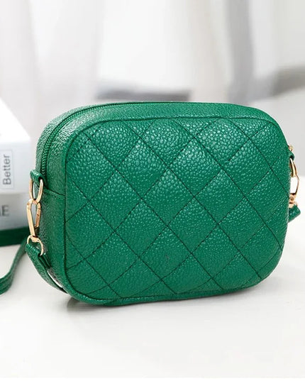 Green quilted handbag on a white surface with a blurred background