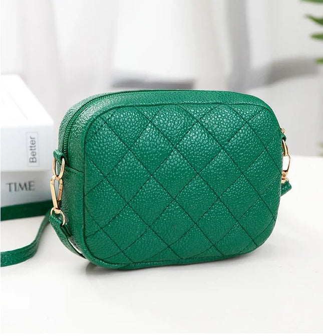 Green quilted handbag on a white surface with a blurred background